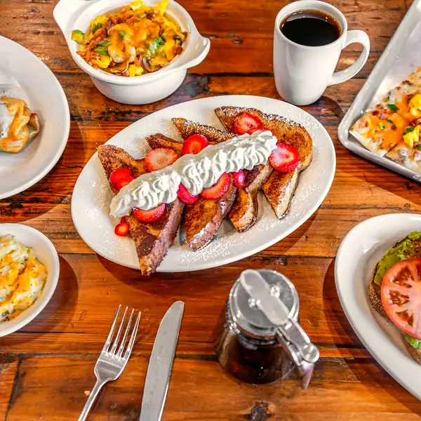 A table of Rooster’s Den breakfast plates with French toast, eggs, biscuits and coffee