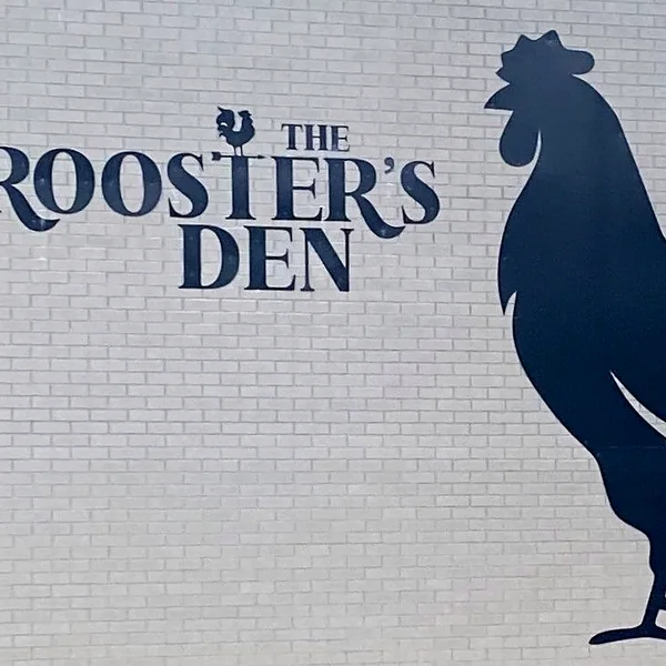 The Rooster’s Den sign with its rooster on the building
