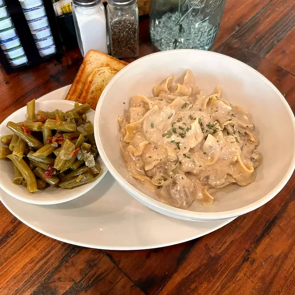 A lunch plate of beef stroganoff over egg noodles with green beans and toast